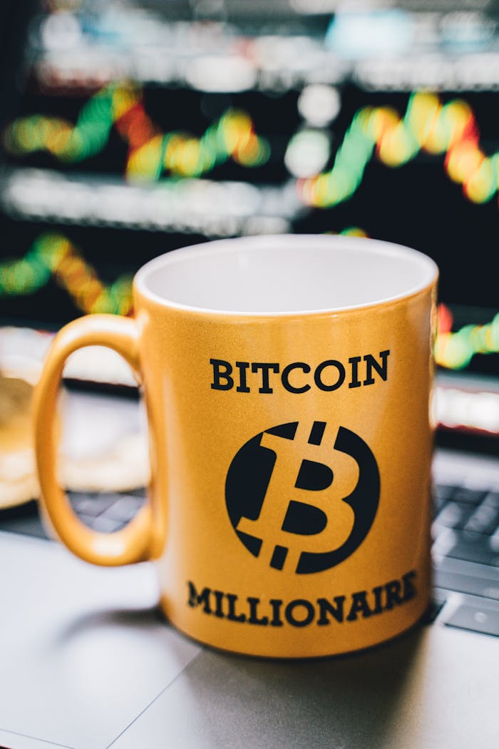 Close-up of a 'Bitcoin Millionaire' mug in front of a vibrant stock chart background.